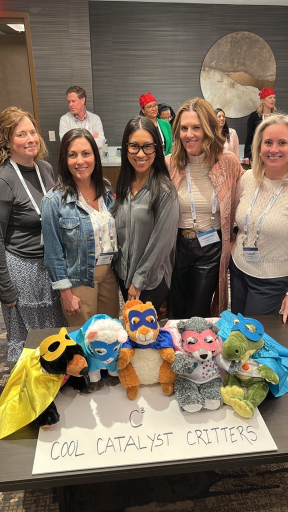 Catalyst employees posing with handmade stuffed animals with a sign reading C3, cool Catalyst critters.
