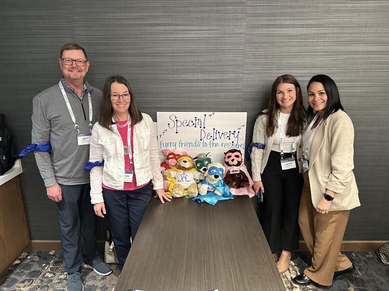 Catalyst employees posing with handmade stuffed animals with a sign reading special delivery, furry friends to the rescue.