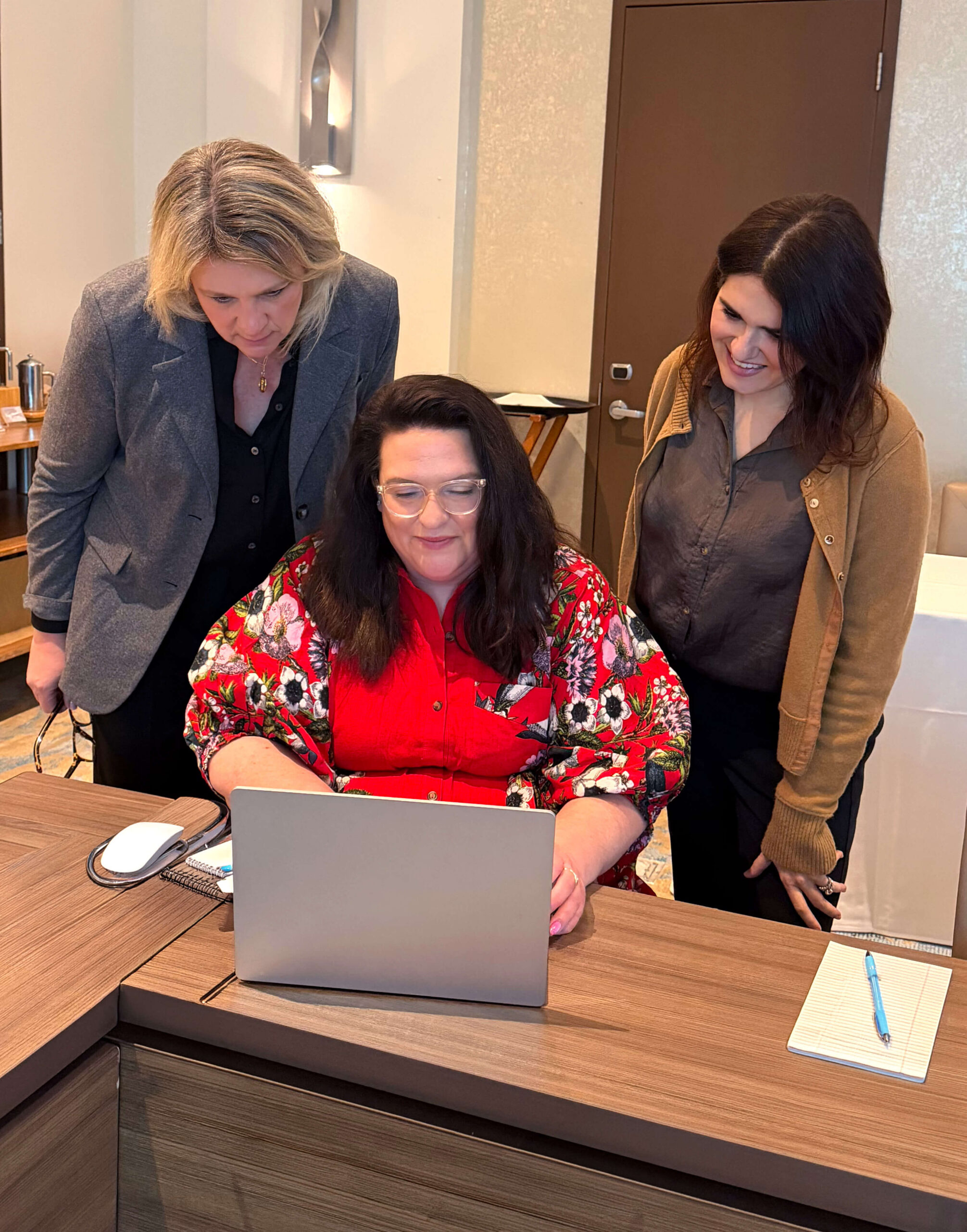 Catalyst employees standing around a laptop, collaborating on work.